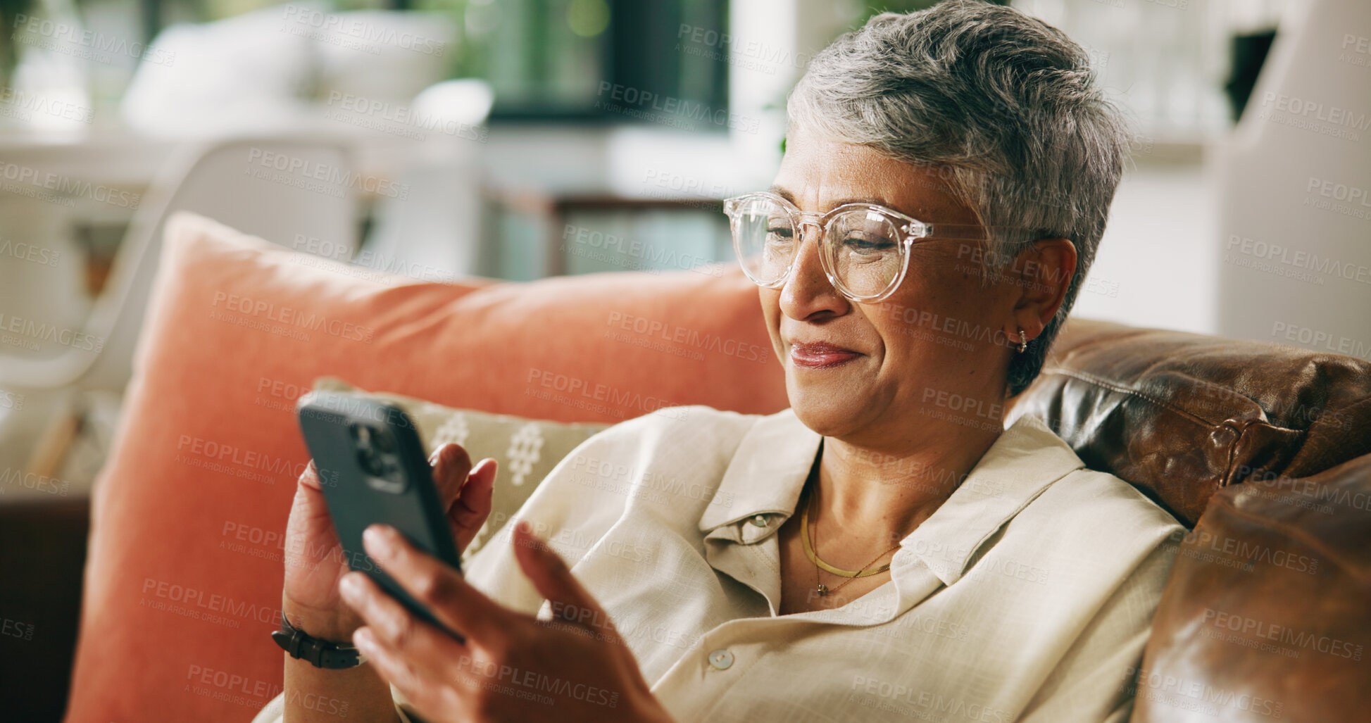 Buy stock photo Mature woman, smartphone and smile on couch with contact, relax and notification on web in home. Person, hone and happy with mobile app, post and texting on social network in lounge at apartment