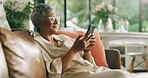 Mature woman, phone and sofa in home with texting, scroll and reading notification in living room. Person, smartphone and smile with mobile app, search and post on social media on couch at apartment