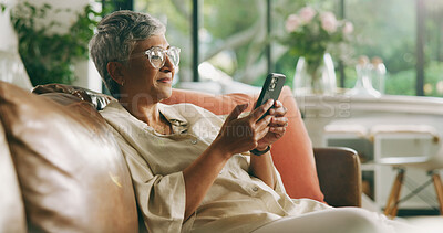 Buy stock photo Mature woman, phone and sofa in home with texting, scroll and reading notification in living room. Person, smartphone and smile with mobile app, search and post on social media on couch at apartment