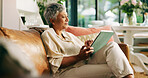 Mature woman, relax and tablet on couch in home, scroll and reading ebook on web in living room. Person, smile and tech with typing, search and streaming film with subscription on sofa at apartment