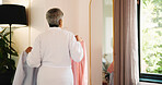 Mature woman, clothes and planning in mirror of bedroom for outfit choice, getting ready and style. Back, fashion and person in home with shirts for garment decision, wardrobe selection and start day