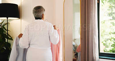 Buy stock photo Mature woman, clothes and planning in mirror of bedroom for outfit choice, getting ready and style. Back, fashion and person in home with shirts for garment decision, wardrobe selection and start day