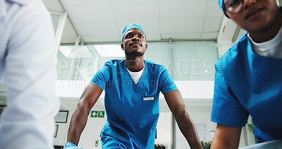 Buy stock photo Team, surgeon and black man pushing stretcher for surgery, medical help and injury in hospital. Clinic POV, rush or low angle of doctor with scrubs and bed for healthcare services, risk and emergency