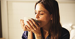 Woman, drinking and coffee on bed at house for morning start, enjoy espresso and smell aroma. Female person, thinking and beverage for peace, nostalgia memories and herbal tea for wellness in bedroom