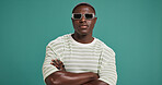 Black man, fashion and sunglasses with arms crossed, style and confidence on green studio background. Portrait, male person or serious African model with accessory, shades or eyewear on mockup space