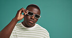 Black man, fashion and sunglasses with portrait, style and confidence on green studio background. Gen Z, male person or serious African model with trendy accessory, shades or eyewear on mockup space