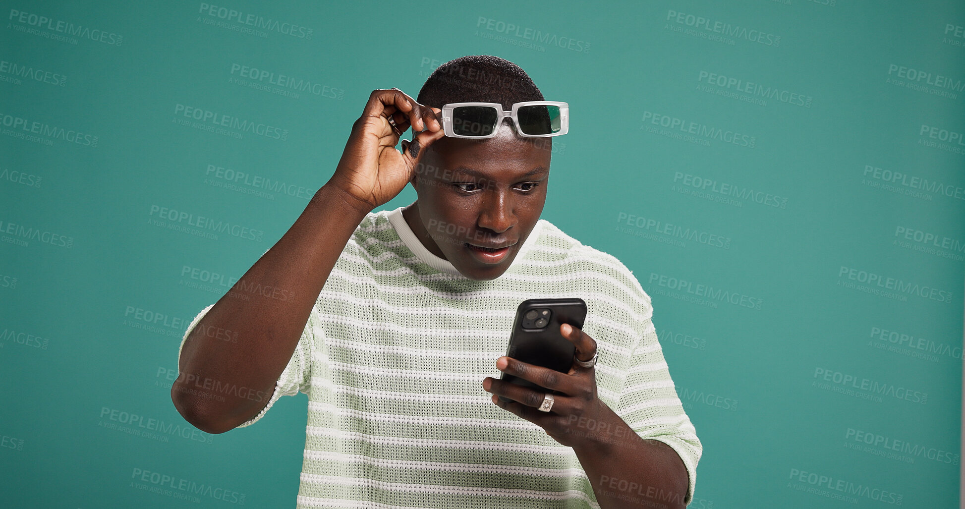 Buy stock photo Surprise, smartphone and black man in studio, wow or announcement on green background. African person, mobile user and cellphone with facial expression, space or shocked with reaction or notification