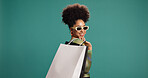 Confident, fashion and woman with shopping bag, studio or happy for discount, mockup space and gift. Green background, shopper and African person with products on sale, smile and customer with shades