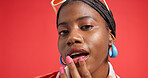 Black woman, portrait and lips with makeup in studio for fashion on a red background. Face, female person or African model with beauty cosmetics, cool accessories or style for cosmetology on space