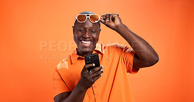 Buy stock photo Excited, fashion or black man with phone in studio for surprise discount, sale or bargain deal. Space, notification or happy model on orange background in trendy sunglasses, good news or cool clothes