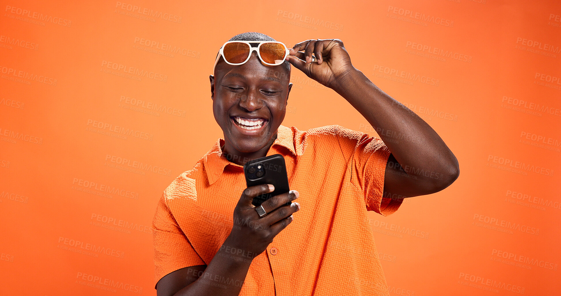 Buy stock photo Excited, fashion or black man with phone in studio for surprise discount, sale or bargain deal. Space, notification or happy model on orange background in trendy sunglasses, good news or cool clothes