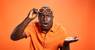 Buy stock photo Surprised, man and question for news, studio and facial expression for revelation, what and fashion. Orange background, shocked and black person with sunglasses, portrait and mockup space for gossip