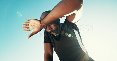 Buy stock photo Tired, sweating and black man by blue sky for running, workout or training for marathon with break. Fatigue, fitness and African male athlete with rest for outdoor cardio exercise from below.