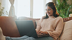 Woman, laptop and relax on sofa with smile, typing and search for movie in lounge at apartment. Girl, happy and chill on couch with computer, streaming or post on social media in living room at house