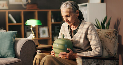 Buy stock photo Grief, old woman and thinking with urn in home for mourning, loss and loneliness in retirement. Sad, sorrow and senior person with depression in lounge for memory, bereavement and reflection of death
