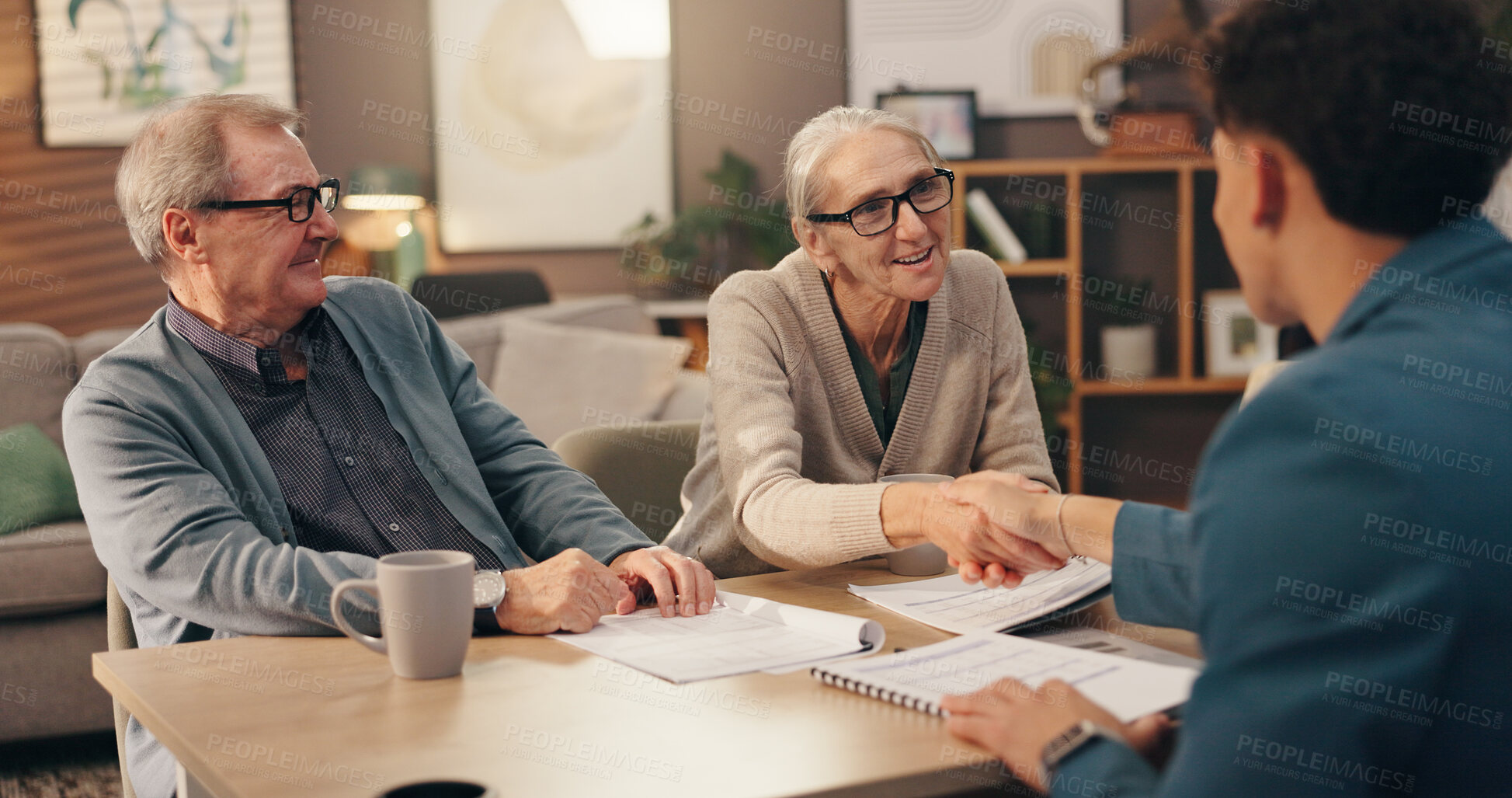 Buy stock photo Elderly couple, documents and handshake with financial advisor for retirement plan at home. Senior man, woman and shaking hands with accountant or paperwork for pension fund or application at house