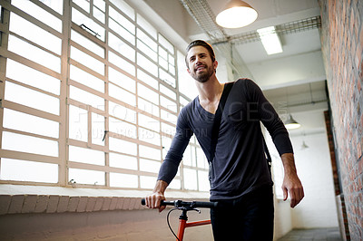 Buy stock photo Man, bike and smile in hallway at office by window, thinking or ready for ride on travel. Person, happy and bicycle in corridor for sustainability, low angle or eco friendly transportation on commute