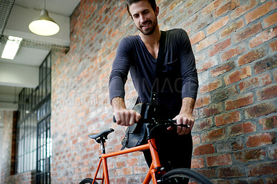 Buy stock photo Bike, carbon footprint and commute with business man in office for start of creative career or job. Brick wall, cycling and environmental with design employee in workplace for net zero travel 