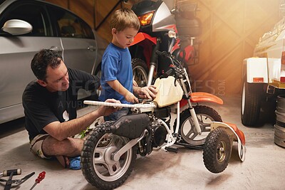 Buy stock photo Family, child and fixing bike in garage at home for teamwork, support and repair with tools. Parent, father and son for bonding, helping and together or teaches as mechanic for motorbike in carport