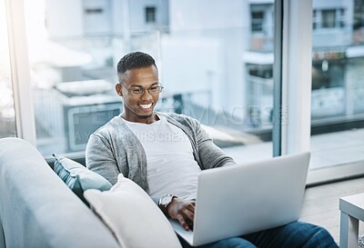 Buy stock photo Black man, couch and home with laptop for relax, watching movies and streaming app. African male person, tech and living room in apartment with social media for day off, online subscription and rest