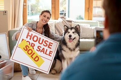 Buy stock photo Woman, pet and new home in living room with picture, happiness and man with smartphone. Homeowners, dog and smile for camera in lounge with joy for moving in, sold real estate sign and pride in house