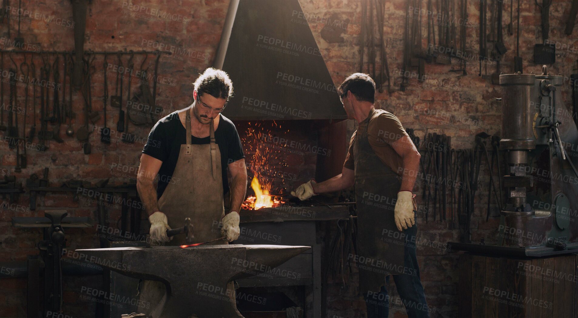 Buy stock photo Hammer, anvil and fire with men working in a foundry for metal work manufacturing or production. Industry, welding and trade with blacksmith craftsmen in a steel workshop, plant or industrial forge