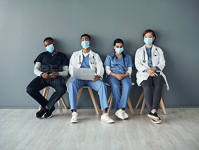 Buy stock photo Chairs, team and tired doctors by wall for interview or public health conference and training meeting. People, medical staff and line for patient rounds or daily briefing, review and medicare.