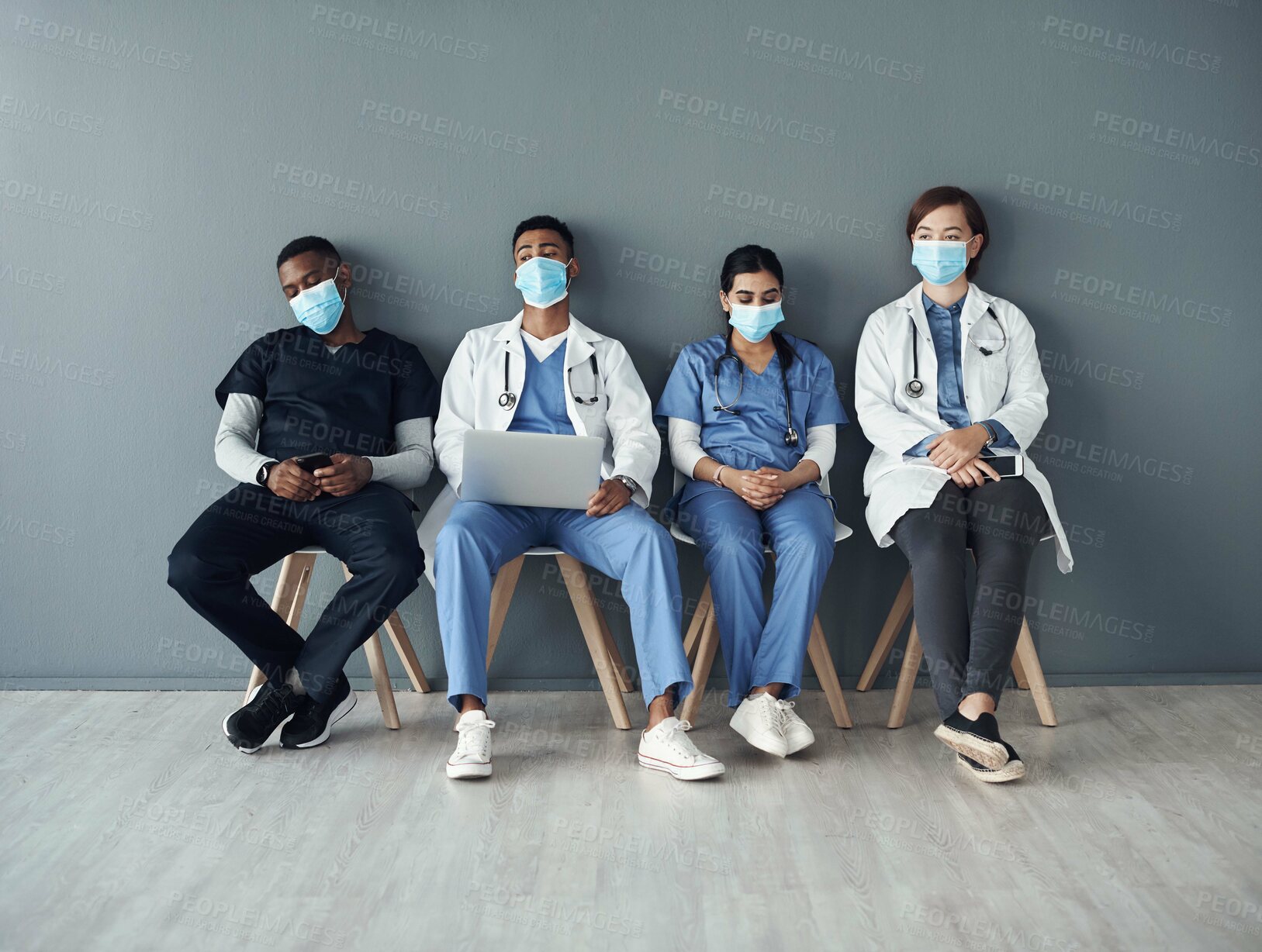 Buy stock photo Chairs, team and tired doctors by wall for interview or public health conference and training meeting. People, medical staff and line for patient rounds or daily briefing, review and medicare.