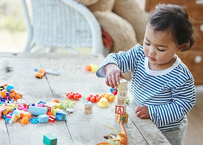 Buy stock photo Baby girl, table and stacking with blocks or toys for playful time, chilldhood or development at home. Little child or cute toddler enjoying youth and playing with cubes, squares or building at house