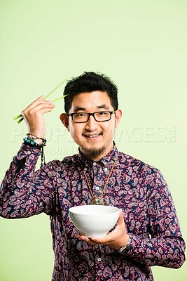 Buy stock photo Studio, portrait and asian man with chopstick for food, nutrition and laughing with confidence. Mockup space, male person and bowl by green background for meal, noodles and eating with happiness
