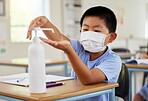Covid, hand sanitizer and school student with mask cleaning, protecting and staying safe in education classroom. Small, little and cute asian boy in learning in study class preventing spread of virus