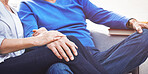 Closeup of loving mature couple holding hands while relaxing together on a sofa at home