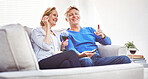 Happy mature couple drinking wine and eating popcorn while watching tv and relaxing together on a sofa at home