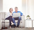 Mature couple browsing online on a laptop while relaxing together on a sofa at home