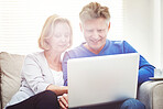 Mature couple browsing online on a laptop while relaxing together on a sofa at home