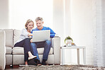 Mature couple browsing online on a laptop while relaxing together on a sofa at home
