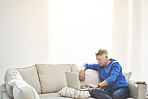 Mature man browsing online on a laptop while relaxing alone on a sofa at home