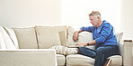 Mature man browsing online on a laptop while relaxing alone on a sofa at home