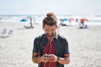 Buy stock photo happy young man using smartphone on beach enjoying sunny day listening to music wearing earphones