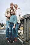 Portrait, child and grandparents on a bridge in a park for adventure, walking and happiness together. Happy, smile and young girl with senior and elderly people on family walk in nature during winter