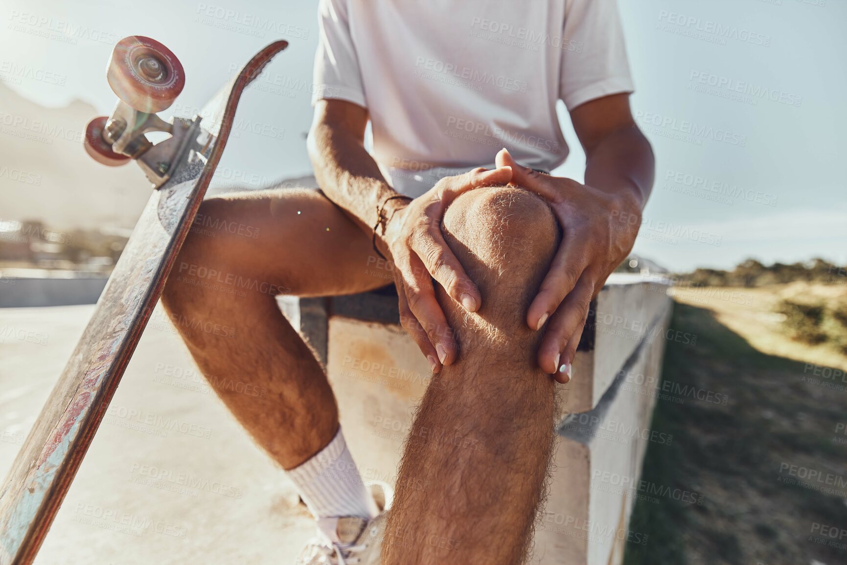 Buy stock photo Knee injury, skateboard and urban city skate park accident with a man with knee pain after workout. Leg pain after sport, fitness and athlete exercise with hands holding a muscle inflammation 