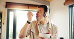Headphones, eating and man with breakfast in kitchen  listening to podcast in morning for self care. Audio tech, health and male person enjoying fruit salad for diet, nutrition or wellness in home.