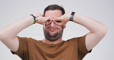 Buy stock photo Binocular, hands and silly man with playful expression or gesture in studio for vision or funny face. Happy male person, comic finger glasses and white background for joke, sign and perspective
