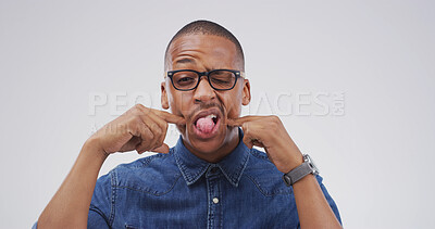 Buy stock photo Portrait, funny face and black man in studio with silly facial expression on white background. Tongue out, mouth and African person with crazy gesture, emoji and playful comedy with glasses for comic