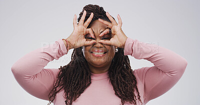 Buy stock photo Binocular, hands and silly woman with expression or playful gesture in studio for vision or funny face. Happy black person, comic finger glasses and white background for joke, portrait or perspective