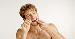 Dental health, floss and man in studio with hygiene, wellness and mouth routine in morning. Oral care, fresh breath and person with string for cleaning teeth with plaque removal by white background.