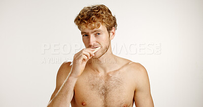 Buy stock photo Dental health, portrait and man brushing teeth in studio for fresh breath, wellness or plaque removal. Morning, hygiene and male person with toothbrush for cleaning mouth by white background space