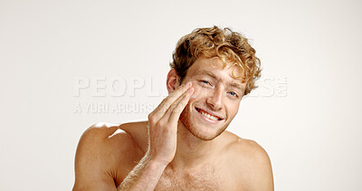 Buy stock photo Portrait, skincare and smile with man in studio for grooming, hygiene or wellness routine. Beauty, happy and lotion with person on white background to apply face cream or moisturizer in bathroom