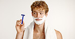 Man, razor and shaving cream in studio for hair removal, depilation and skincare with towel. Beard grooming, foam and person on white background space with blade, thinking or routine facial treatment