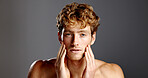 Man, beauty and facial hair in portrait for skincare, grooming and dermatology on a grey background. Redhead, self care and male model serious with cosmetics, confidence or beard with hand on face